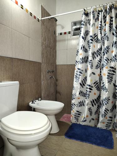 a bathroom with a toilet and a shower curtain at Cabañas Mónika III Norte in Huerta Grande