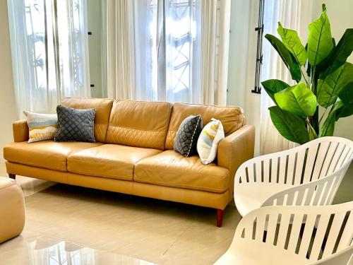 a living room with a brown couch and two white chairs at Soulful Serenity in Steer Town
