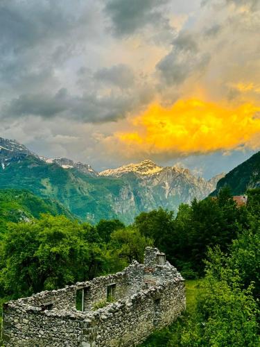 an old stone building with mountains in the background at Guesthouse Gjoni Theth in Theth