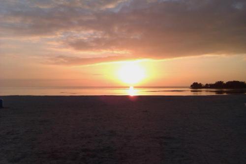 a sunset on a beach with the sun in the sky at Vakantie Chalet Makkum in Makkum