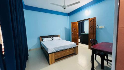 a bedroom with blue walls and a bed and a table at RL Holiday Inn in Jaffna