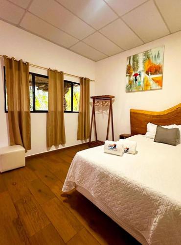 a bedroom with a bed and two windows at Hotel Tunco Lodge in La Libertad