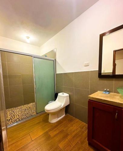 a bathroom with a toilet and a sink and a mirror at Hotel Tunco Lodge in La Libertad