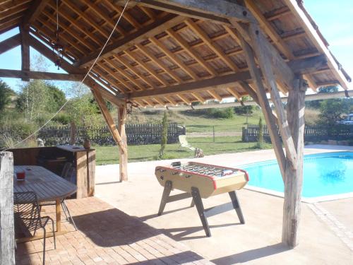 een houten paviljoen met een tafel en een zwembad bij Gite du Domaine de Bombes in Mostuéjouls