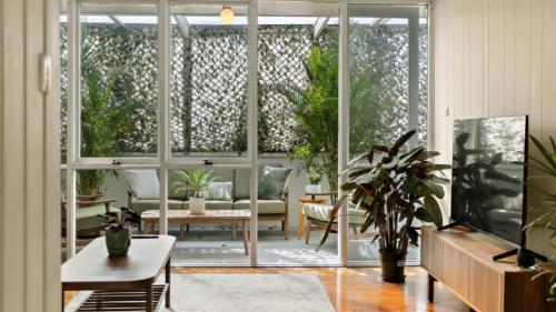 a living room with a sliding glass door with plants at Quirky and Captivating Kurra in Hawks Nest