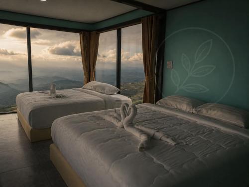 two beds in a room with large windows at The Forest View ภูทับเบิก in Ban Maeo Thap Boek