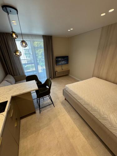 a bedroom with a bed and a desk and a kitchen at S14 Apartment in Vilnius