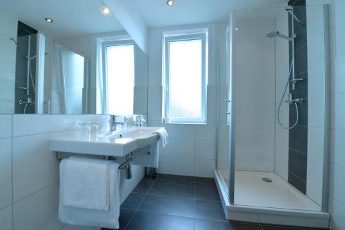 y baño blanco con lavabo y ducha. en Hotel-Restaurant "Zum Alten Fritz", en Mayen
