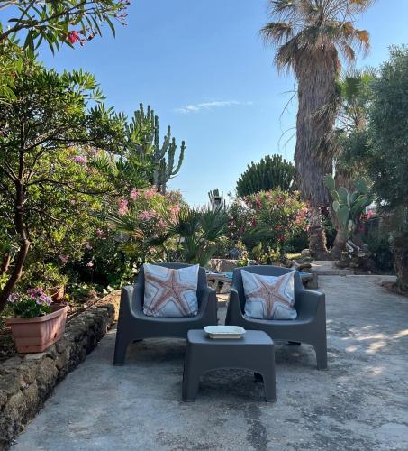two chairs and a coffee table in a garden at Villamare in Custonaci