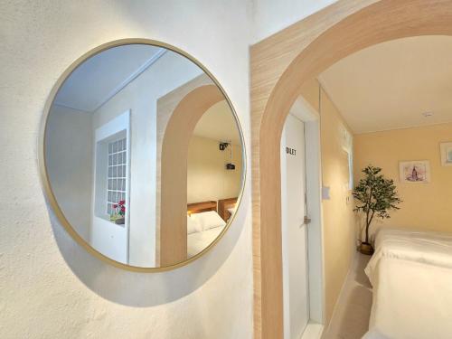 a round mirror on a wall in a bedroom at 스테이동백 in Jeonju