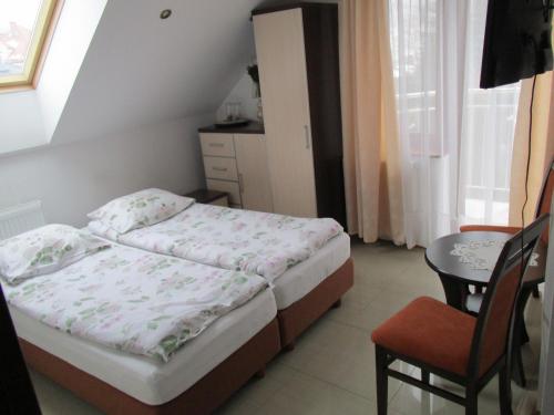a bedroom with a bed and a chair and a table at Gościniec Klejnot in Borowo