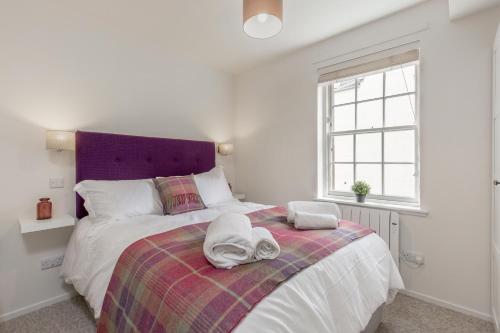 um quarto com uma cama grande e uma cabeceira de cama roxa em The Wee Thistle em Edimburgo