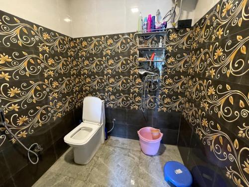 a bathroom with a toilet and a black and gold wallpaper at Ashirwad Homestay in Bhowāli