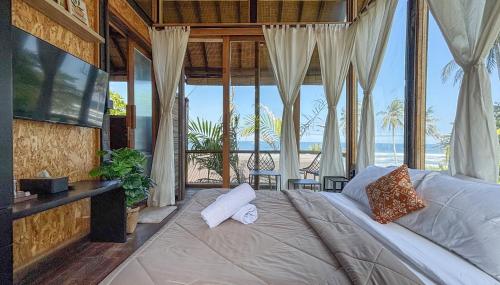 a bedroom with a large bed with a view of the ocean at Salty Cabin Sunset Views Yeh Leh Beach in Balian