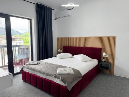 a bedroom with a large bed and a large window at Pensiunea LOFT Căciulata in Caciulata