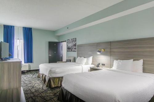 a hotel room with two beds and a flat screen tv at Wingate by Wyndham North Little Rock in North Little Rock