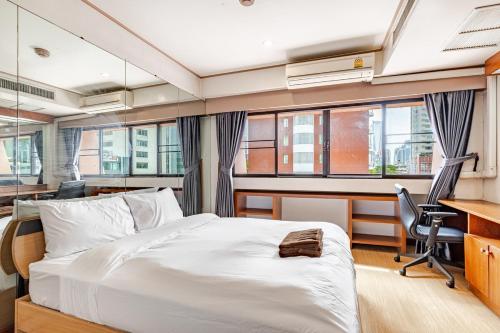 a bedroom with a bed and a desk and some windows at 2BR Duplex in central Chitlom in Bangkok