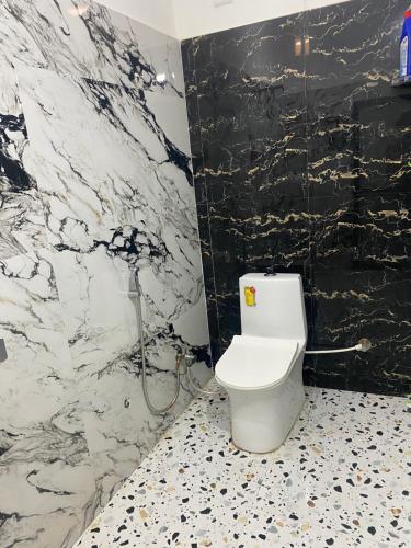a bathroom with a white toilet and a black wall at Vedavit Bhavanam in Gaya