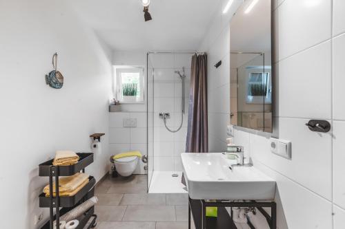 a white bathroom with a sink and a shower at Seeblick Homes in Fuschl am See