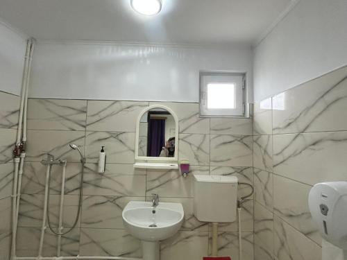 a bathroom with a sink and a toilet and a mirror at Camere de închiriat Doriana in Vama Veche
