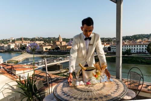 un uomo in smoking in piedi sopra un balcone di Hotel Principe a Firenze