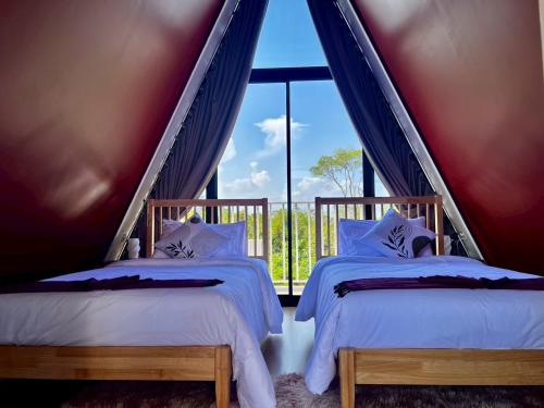two beds in a room with a large window at ฟูจิจันท์ fujijun cafe&resort in Ban Na Khieo