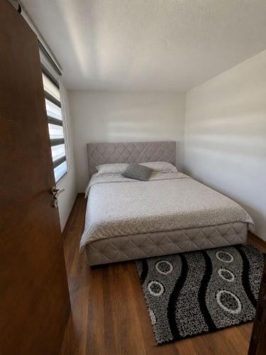 a small bedroom with a bed and a rug at Vikendica Mavi in Gradačac