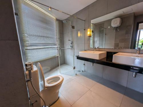 a bathroom with two sinks and a toilet and a mirror at Oceanfront condo 3-2-01- Nilaveli in Nilaveli
