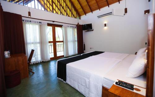 a bedroom with a large white bed and windows at Miracle Resorts & Villas in Polonnaruwa