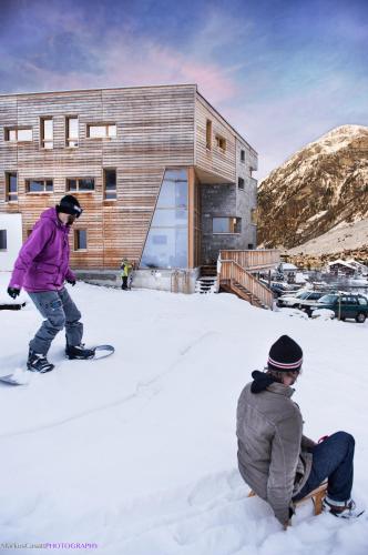 two people on snowboards in the snow in front of a building at Hotel Steinbock Vals in Vals