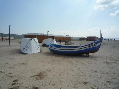 a blue boat sitting on the beach with a tent at Casa Mar in Costa da Caparica