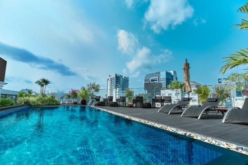 a swimming pool with chaise lounge chairs and a city skyline at Bach Suites Saigon, a Member of Design Hotels in Ho Chi Minh City
