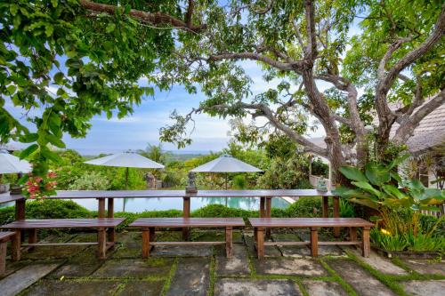 a picnic table under a tree with umbrellas at Villa Olala Penida in Nusa Penida