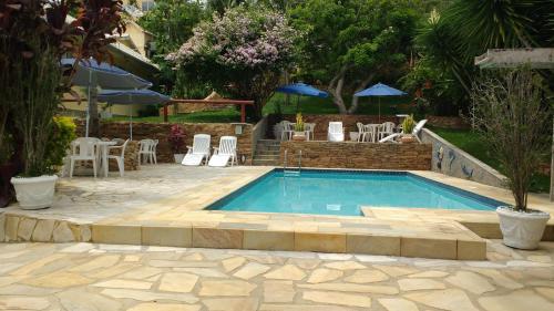 a swimming pool in a yard with chairs and umbrellas at 3 Palmeiras Guest Lounge in Miguel Pereira