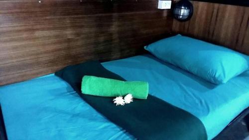 a bed with a green comforter and a pillow at Czone Hostel in Ko Tao