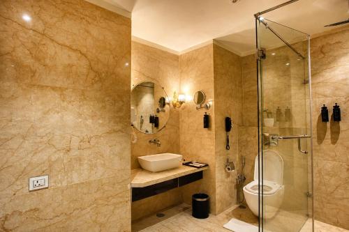 a bathroom with a shower and a sink and a toilet at Pride Hotel & Convention Centre Indore in Indore