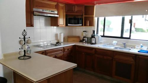 a kitchen with wooden cabinets and a white counter top at Mayan Vidanta Villas GOLF a 800 mt de la playa in Acapulco