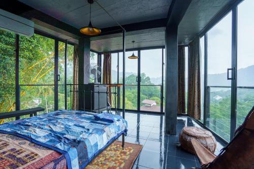 a bedroom with a bed in a room with windows at Kandyan Mist Retreat in Kandy
