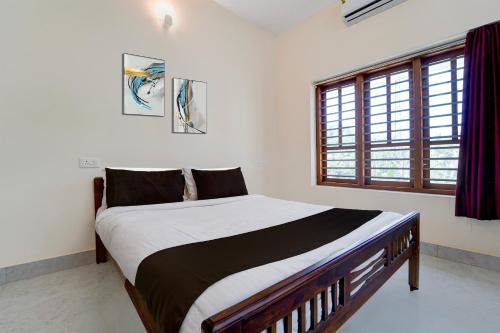 a bedroom with a large bed and a window at Super Collection O Technopark Phase 1 Formerly Snehalayam in Trivandrum