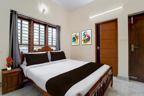 a bedroom with a large bed and a wooden door at Super Collection O Technopark Phase 1 Formerly Snehalayam in Trivandrum