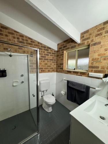 a bathroom with a shower and a toilet and a sink at Clock Tower Motor Inn in Coonabarabran