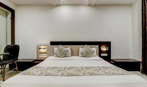 a bedroom with a large white bed and a chair at FabHotel CSFC in Bhopal