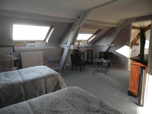 a bedroom with two beds and a table and chairs at Victoria Arromanches B&B in Tracy-sur-Mer