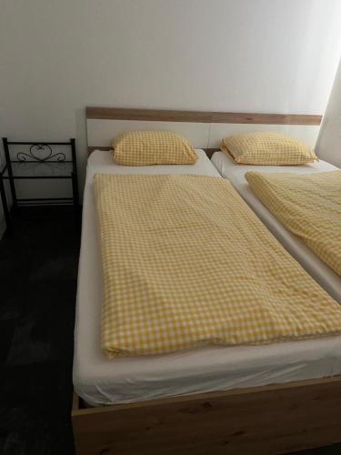 two beds with yellow and white sheets and pillows at Double Room Stegersbach in Stegersbach