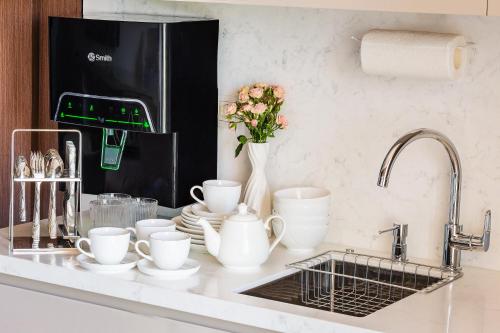 a kitchen counter with cups and plates and a sink at Central one new apartments - panoramic skyline & boulevard in Tashkent