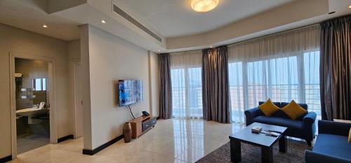 a living room with a blue couch and a tv at Loumage S Suites and Spa in Manama