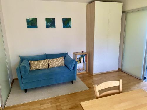 a living room with a blue couch and a chair at Häuschen mit Gartenblick in Idstein