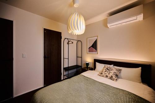 a bedroom with a bed and a chandelier at Black Grove House in Ginowan
