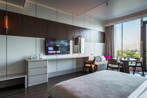 a hotel room with a bed and a tv and a table at Central one new apartments - panoramic skyline & boulevard in Tashkent