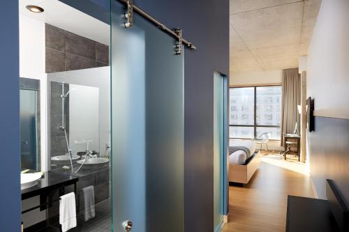 un baño con una puerta de cristal que conduce a un dormitorio en Le Dauphin Montréal Centre-Ville en Montreal